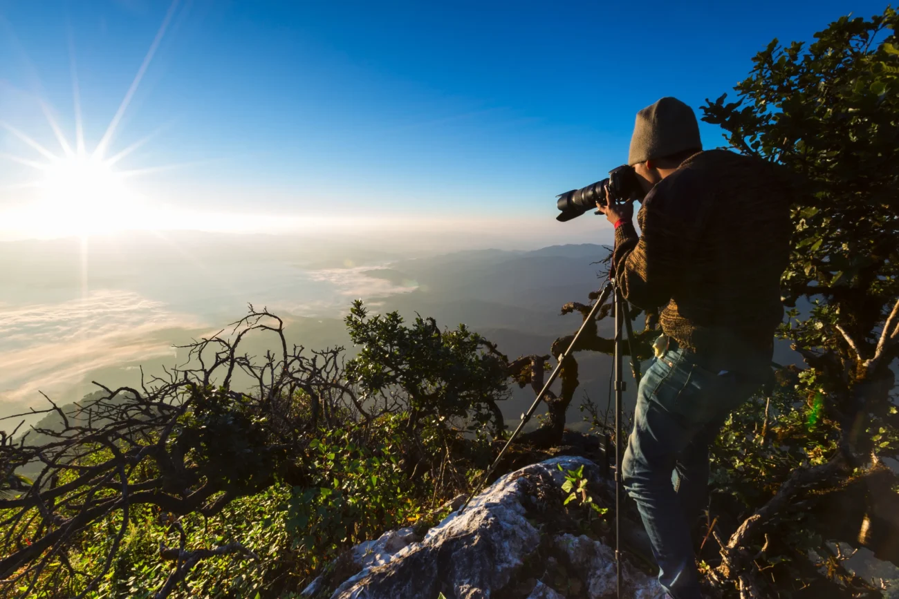 Muž fotí na okraji skály. 