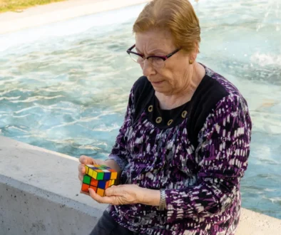 Babička sedí u fontány a skládá Rubikovu kostku.