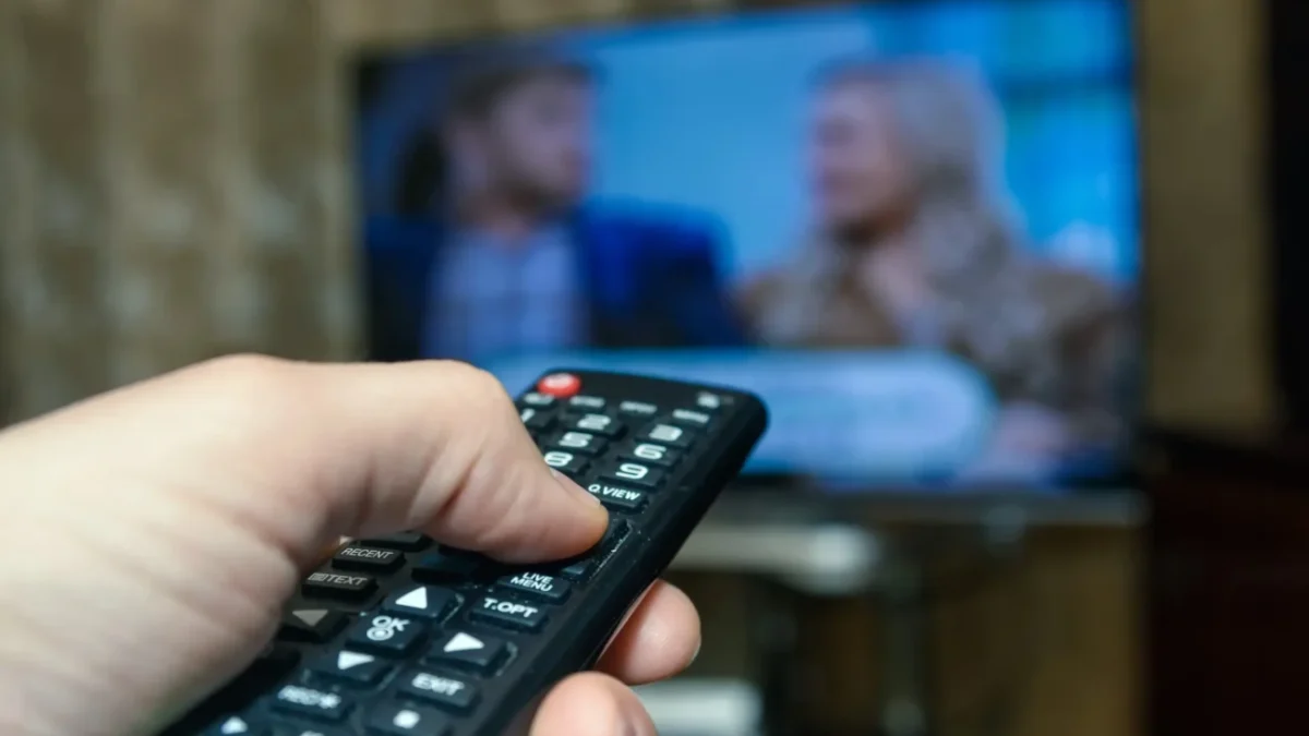 Člověk míří ovladačem na TV.