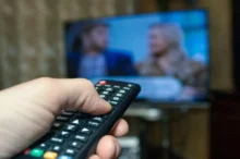 Člověk míří ovladačem na TV.