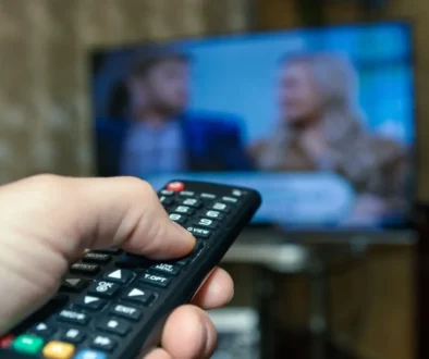 Člověk míří ovladačem na TV.