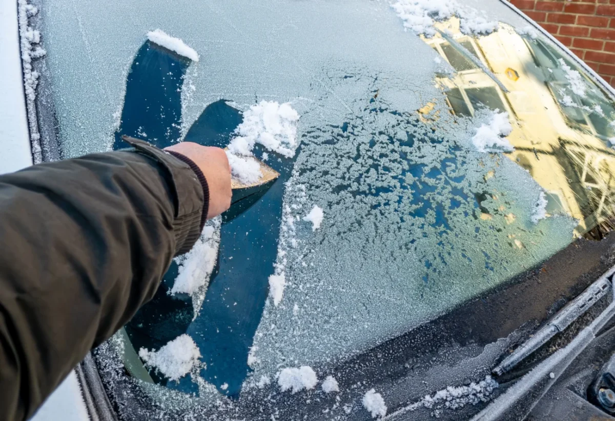 člověk škrábe sklo auta