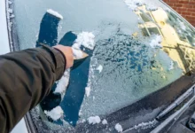 člověk škrábe sklo auta