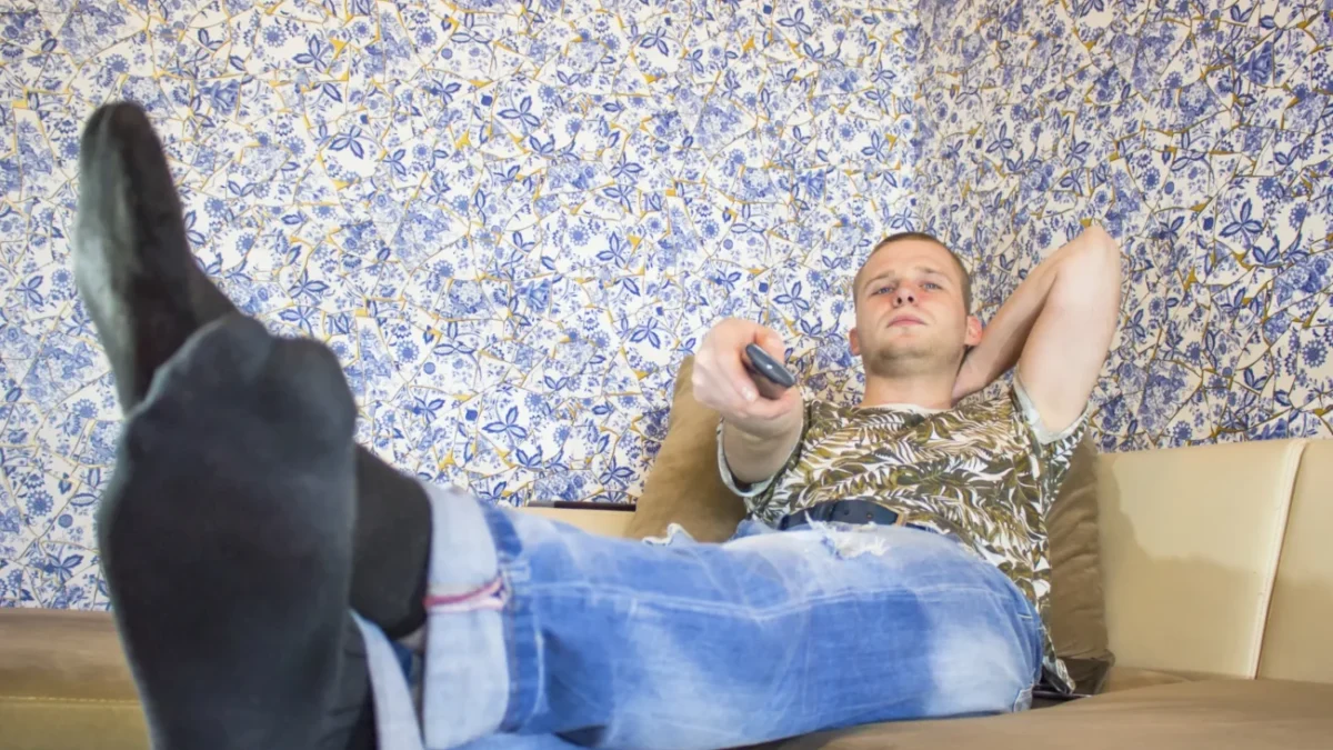 Muž sedí na gauči s nohama nahoře.