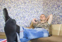 Muž sedí na gauči s nohama nahoře.