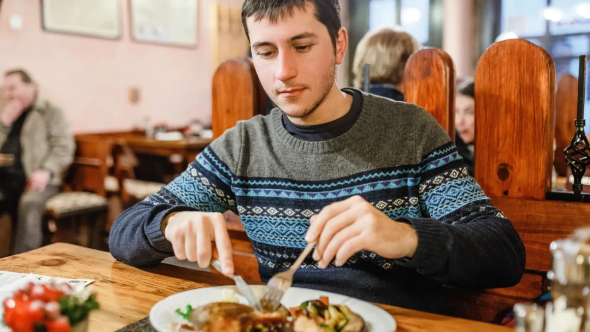 Muž sedí v restauraci a jí.