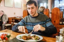 Muž sedí v restauraci a jí.