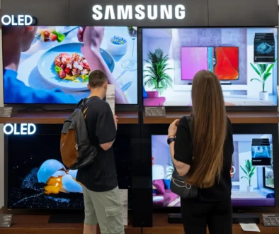 Lidé stojí před televizemi.