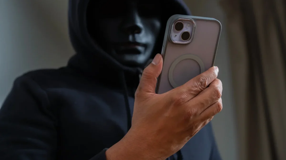 Muž v masce kouká na telefon.