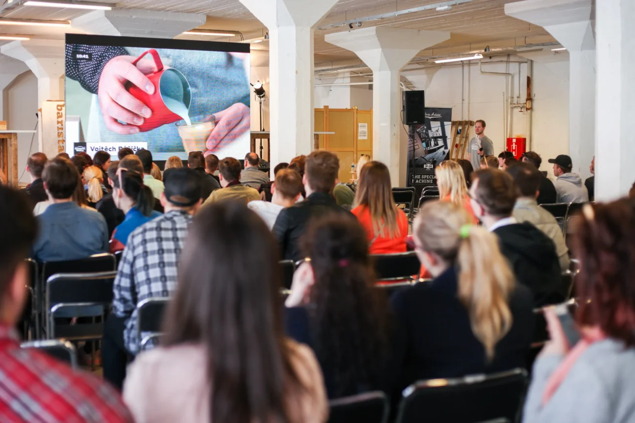 Lidé sedí na židlích a dívají se na plátno. 