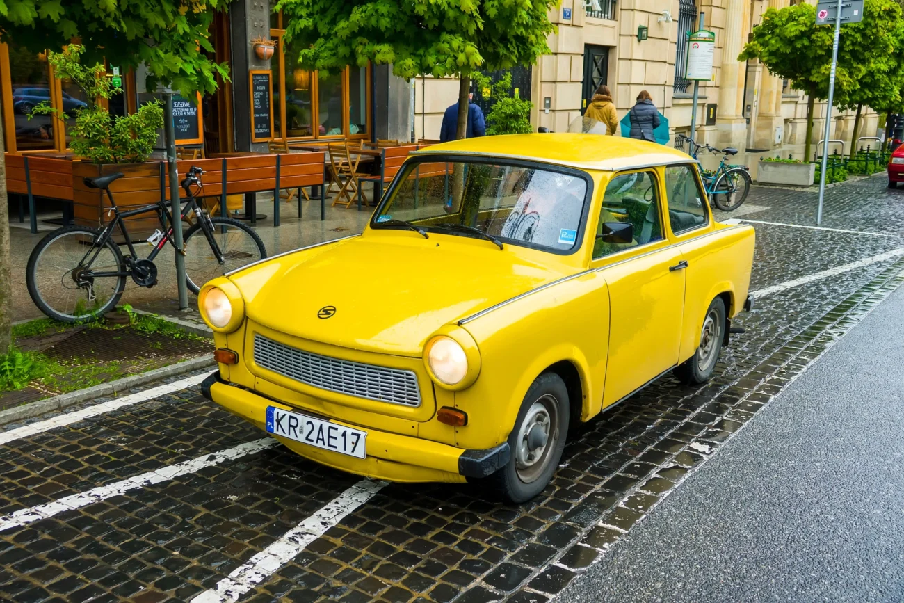 Na ulici stojí žlutý trabant.