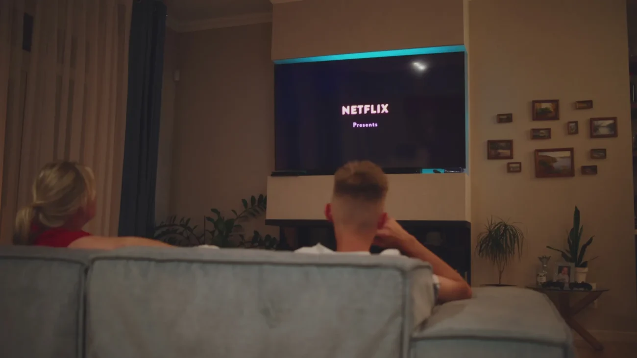 Lidé sedí na gauči a dívají se na Netflix. 