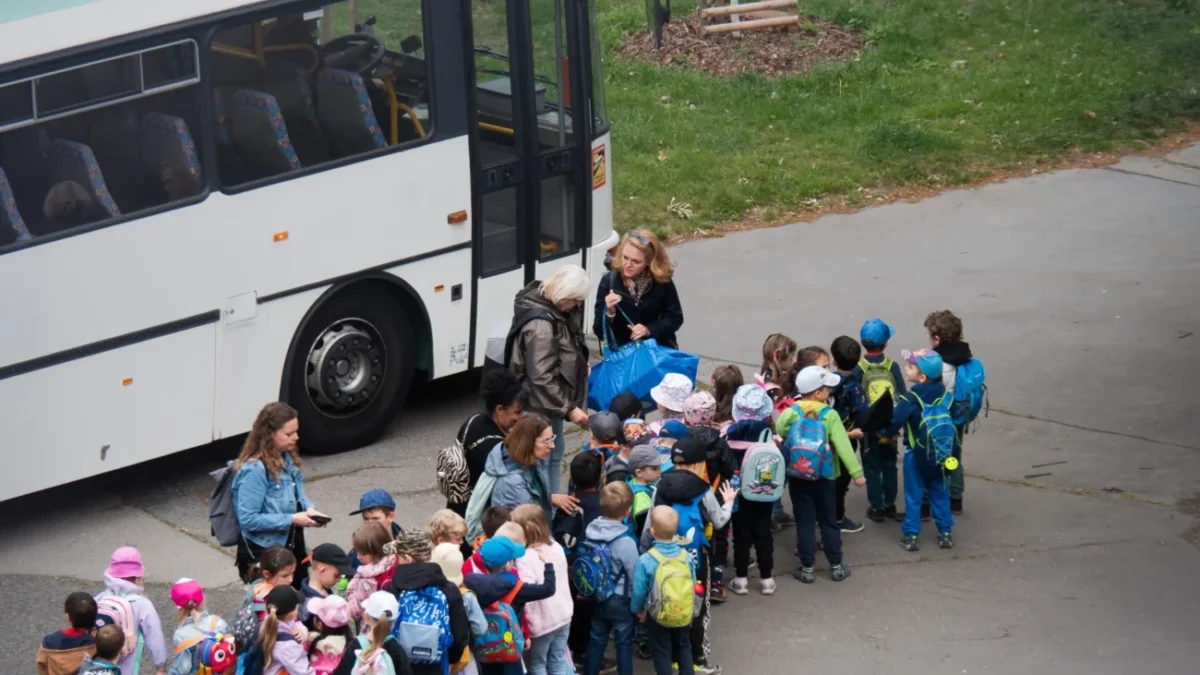 Děti stojí seřazené před autobusem.