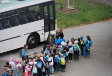 Děti stojí seřazené před autobusem.