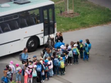 Děti stojí seřazené před autobusem.