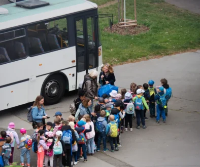 Děti stojí seřazené před autobusem.
