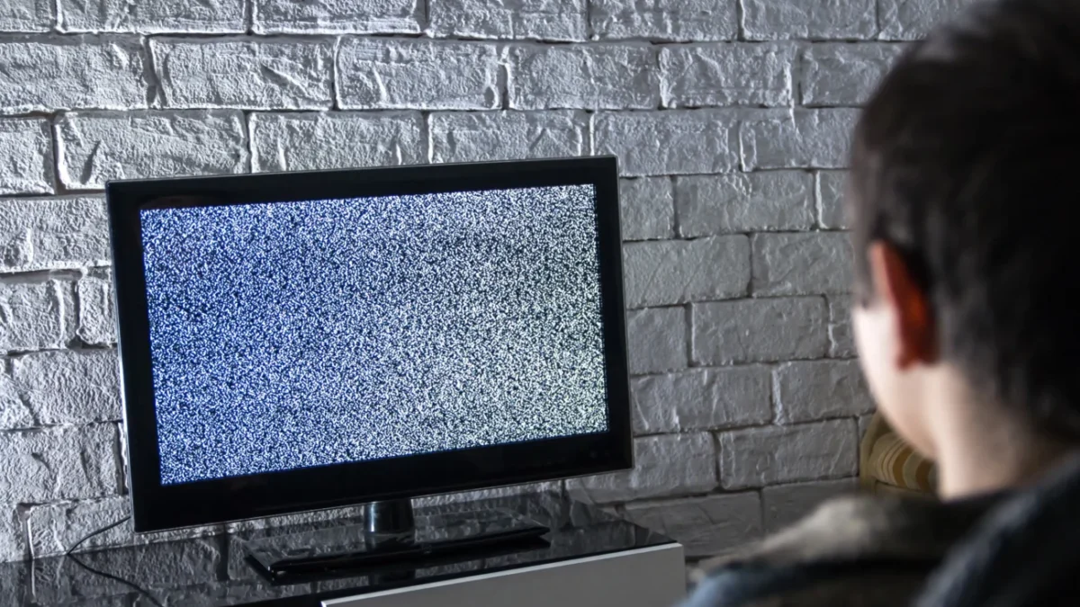 Muž se dívá na televizi, která nic nevysílá.