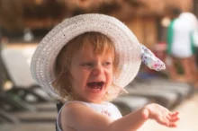 Holčička s kloboučkem na hlavě se usmívá.