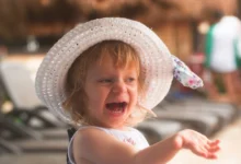 Holčička s kloboučkem na hlavě se usmívá.