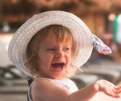 Holčička s kloboučkem na hlavě se usmívá.