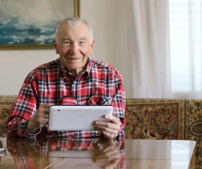 Děda s telefonem v ruce sedí u stolu.