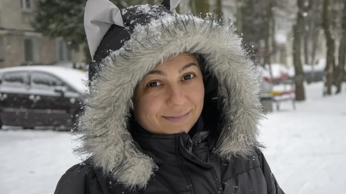 Žena s kapucí na hlavě stojí venku.