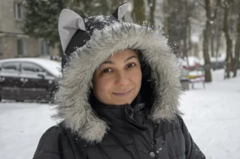 Žena s kapucí na hlavě stojí venku.