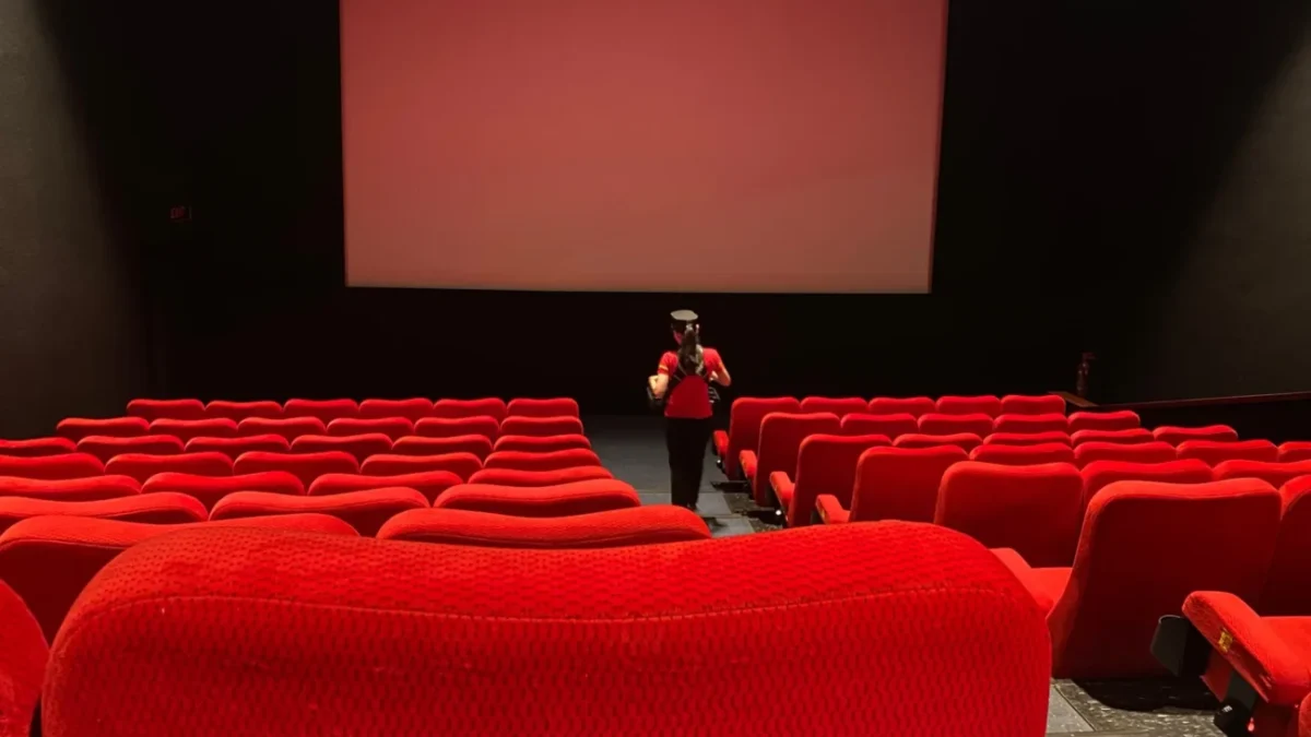 Žena se prochází uličkou v kině.