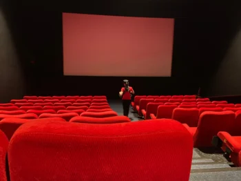 Žena se prochází uličkou v kině.