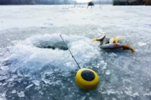 Ryba s prutem leží u díry v ledu.