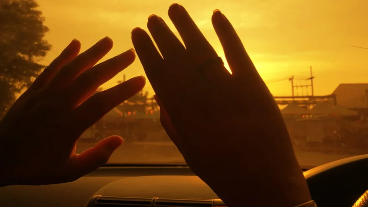 Za okýnkem v autě jsou zdvižené ruce.