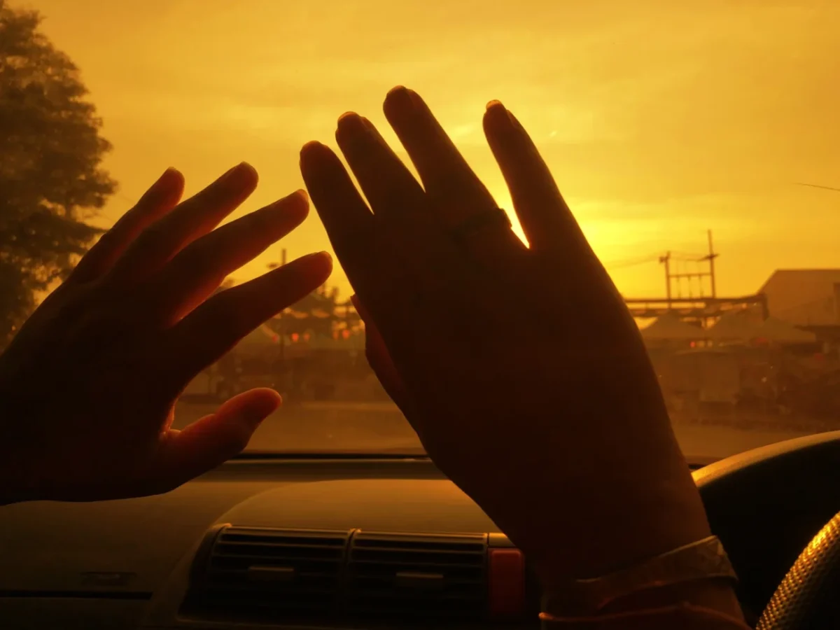 Za okýnkem v autě jsou zdvižené ruce.