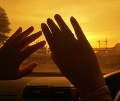 Za okýnkem v autě jsou zdvižené ruce.