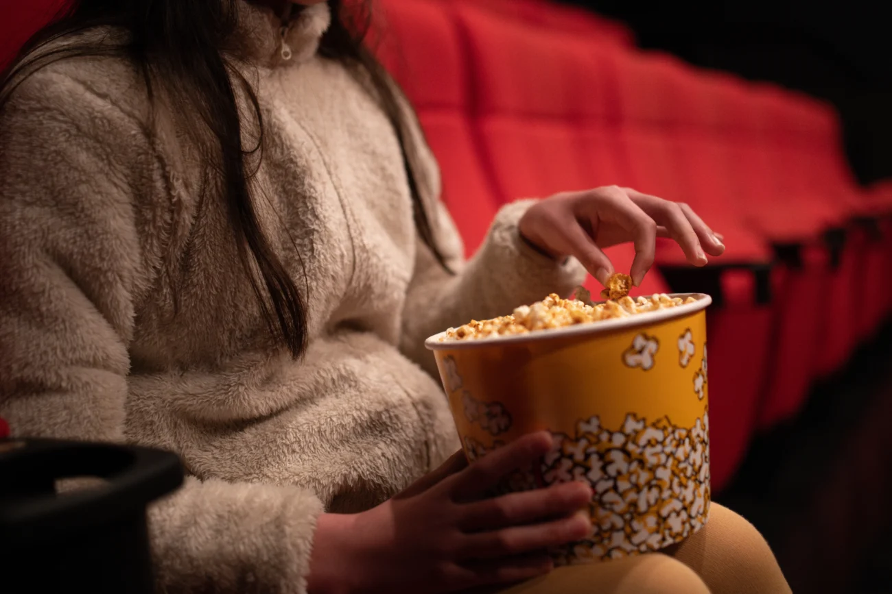 dívka si dává popcorn v kině