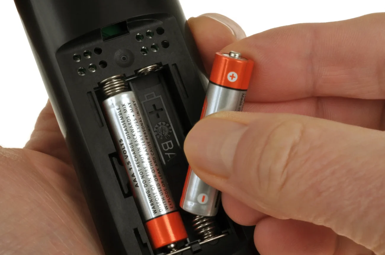 Člověk do ovladače vkládá baterky.