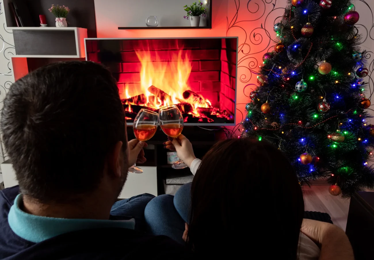 Lidé sedí před televizí, na které je puštěný krb.