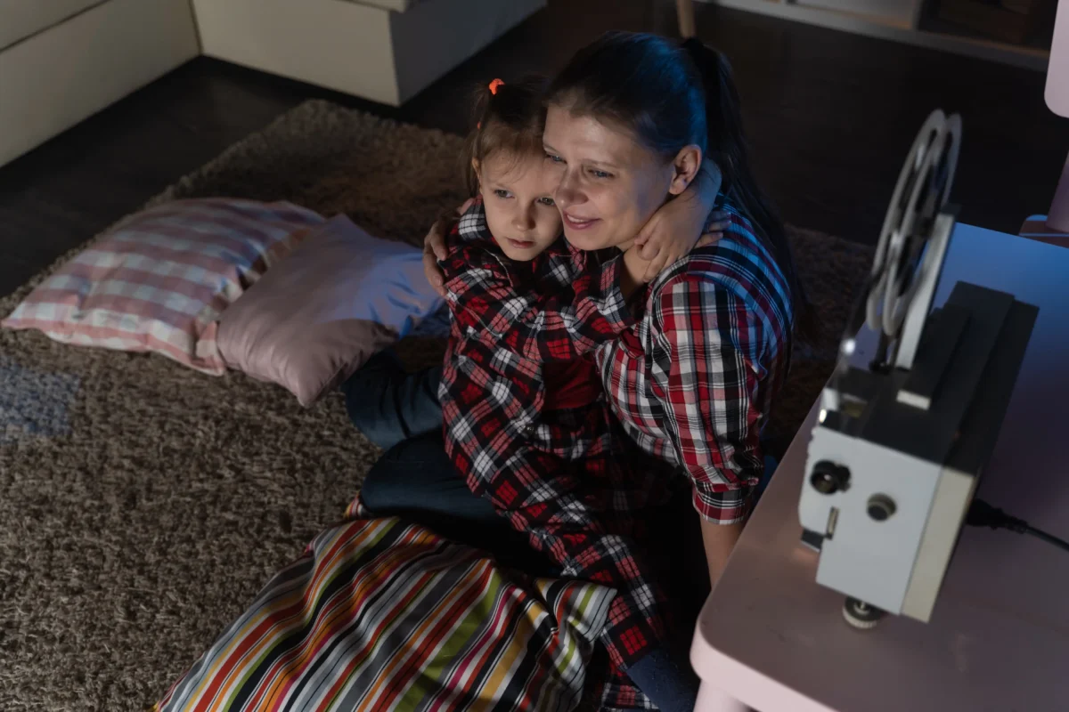 Žena s holčičkou sedí na zemi. 