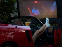 Člověk se z auta dívá na promítaný film.