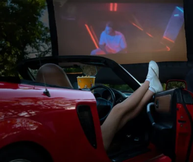 Člověk se z auta dívá na promítaný film.