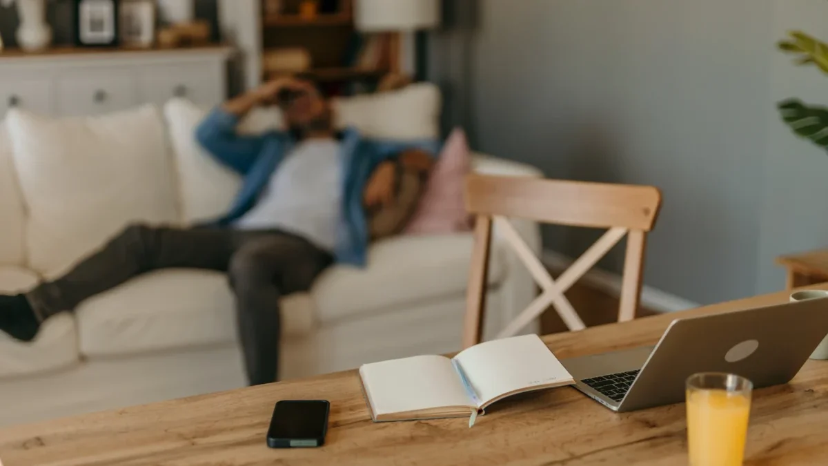 Na stole leží notebook s knihou a pitím.