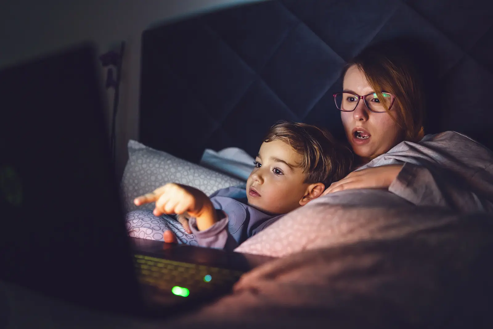 žena s dítětem v posteli sledují film na notebooku