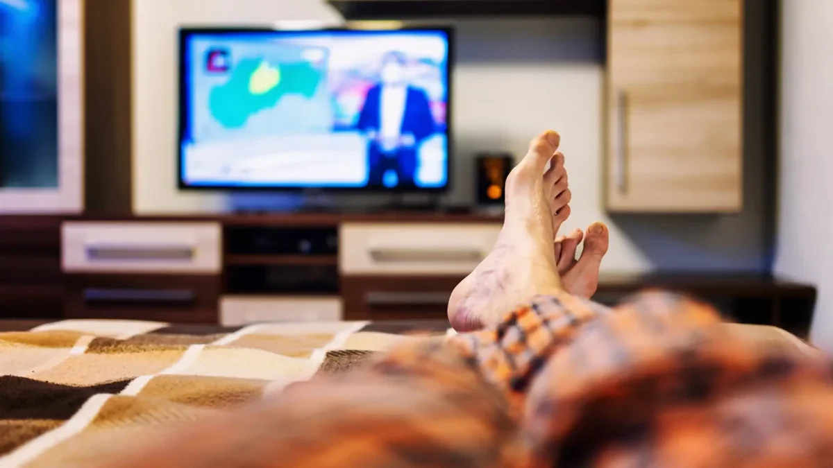 muž se dívá z postele na televizi