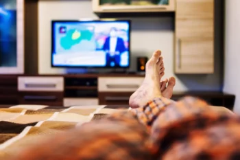 muž se dívá z postele na televizi