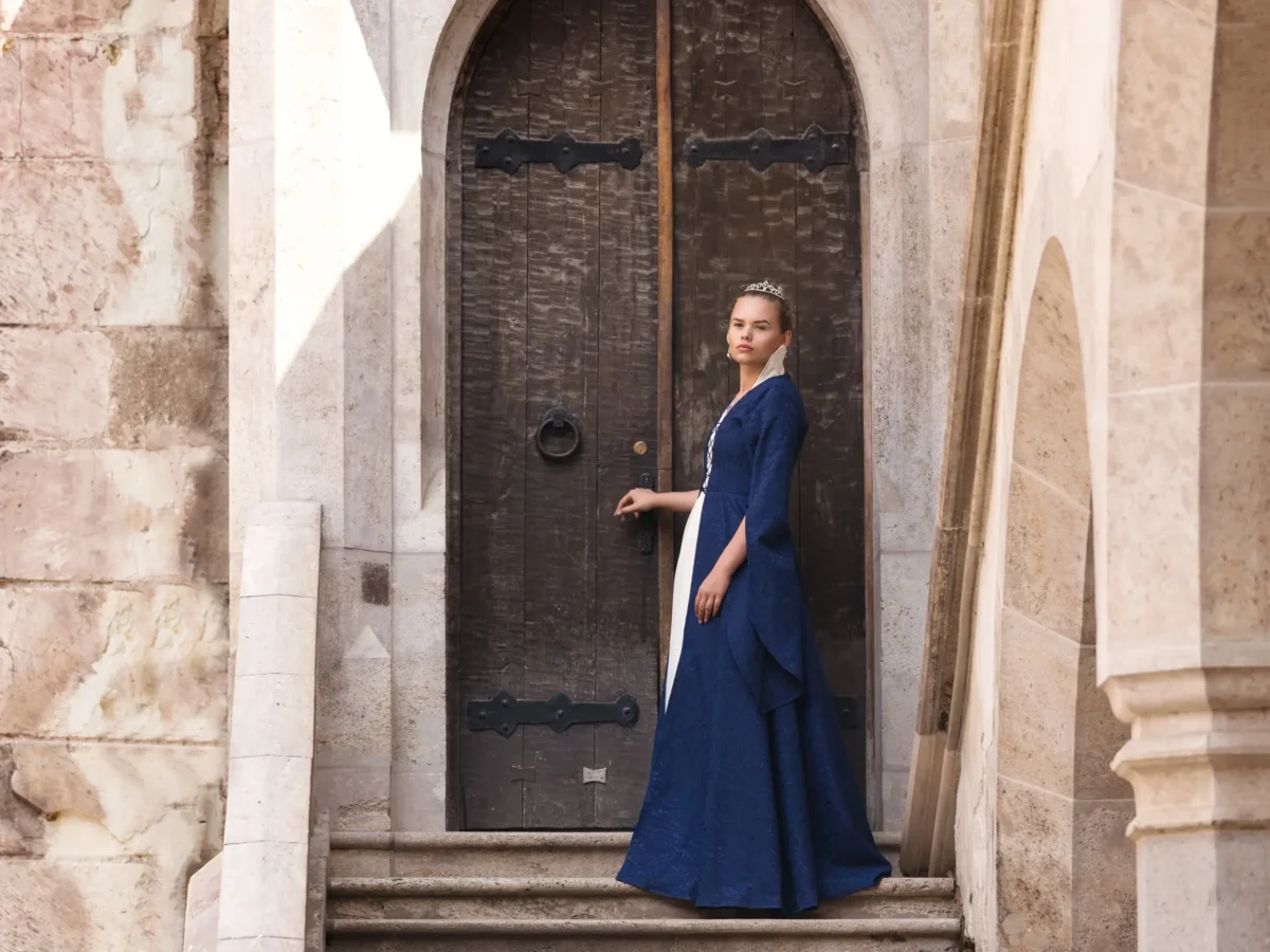 Žena oděná jako princezna stojí na schodech. 