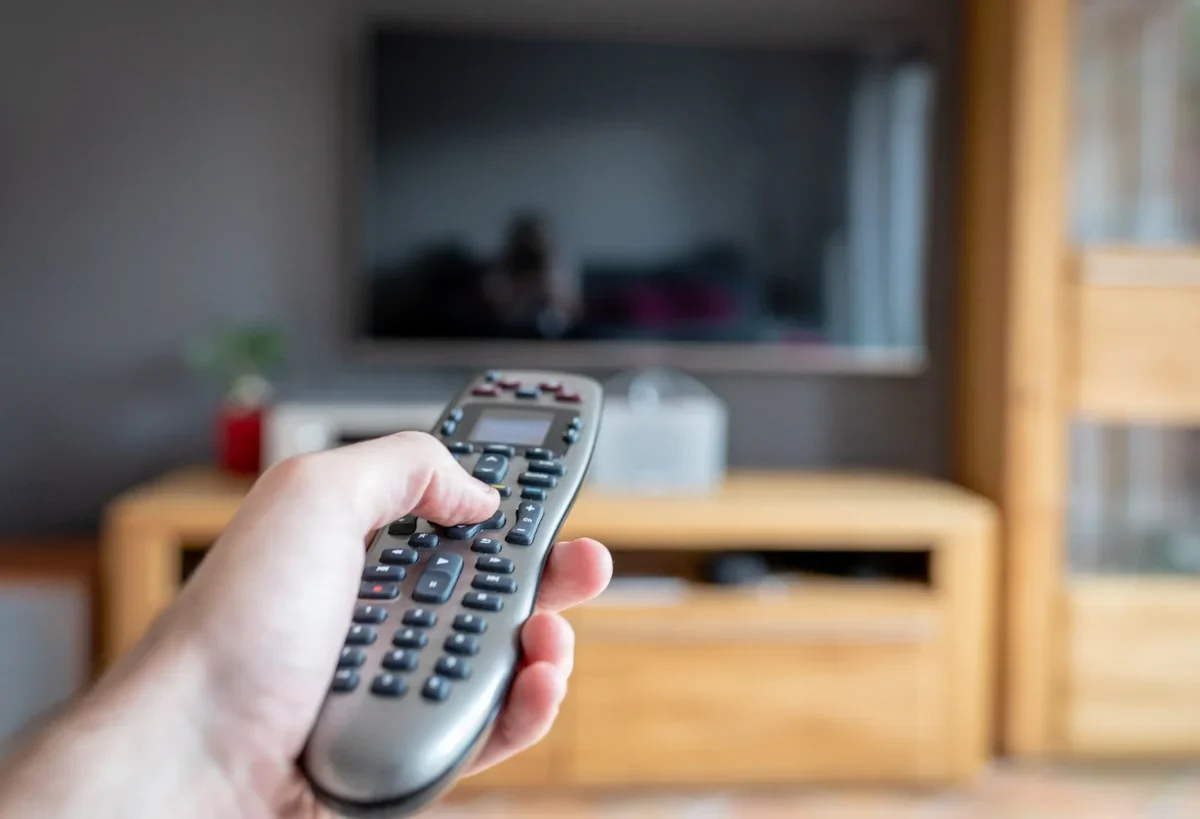 člověk drží ovladač od TV