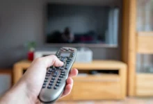 člověk drží ovladač od TV