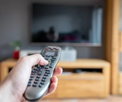 člověk drží ovladač od TV