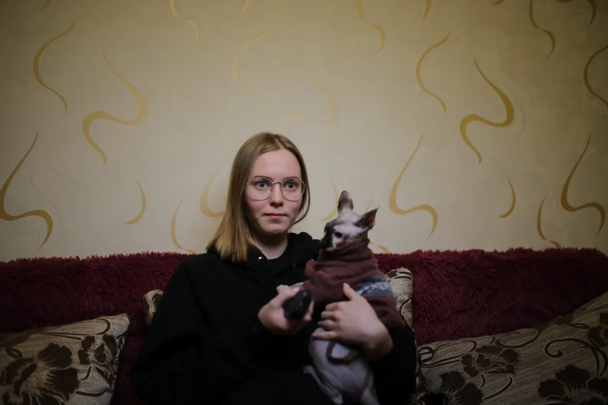 Žena s kočkou sedí na gauči. 