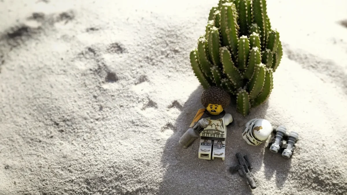 LEGO postavička leží na pláži.