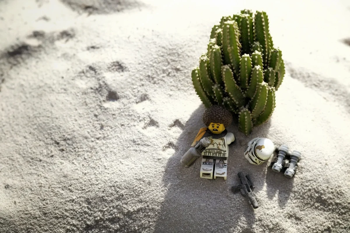 LEGO postavička leží na pláži.